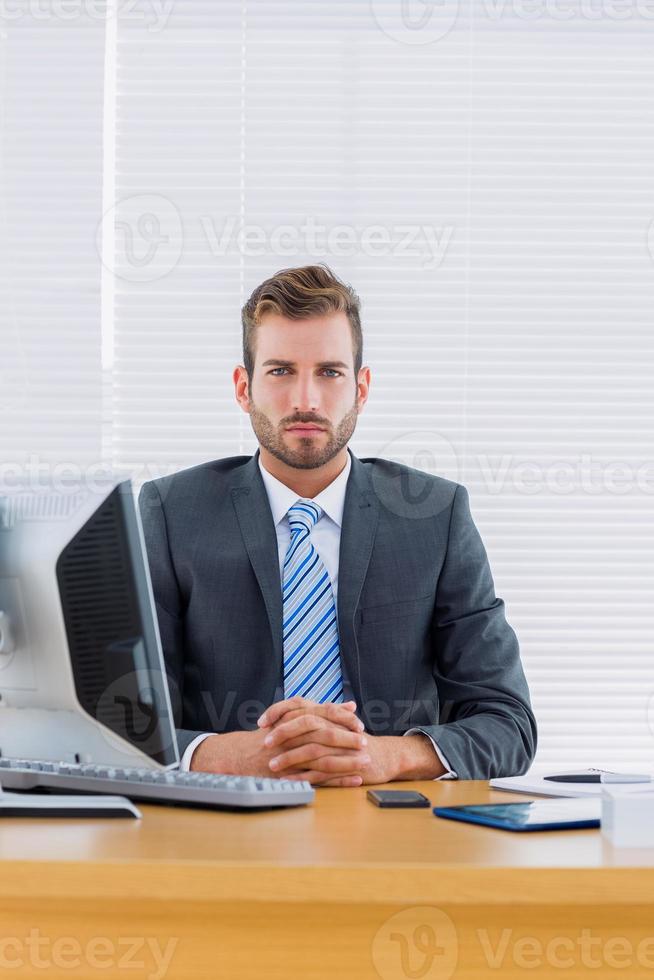 Serious businessman with computer at office desk photo