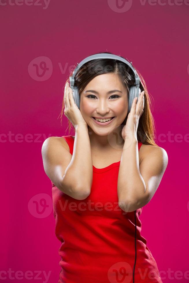 Happy Asian Woman listening to music on headphones. photo