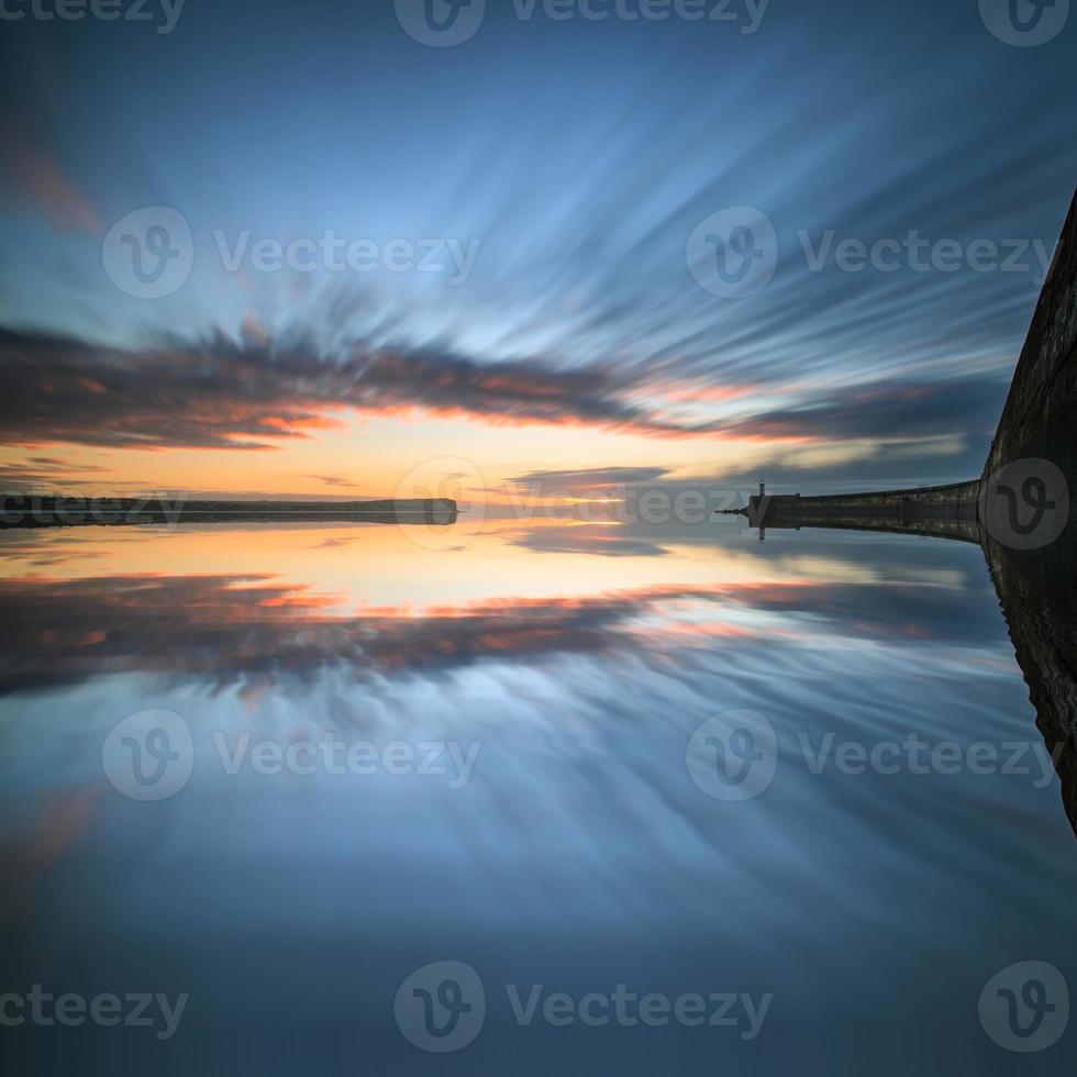 Sunrise Sky Over Calm Water Ocean With Lighthouse And Harbor Stock Photo