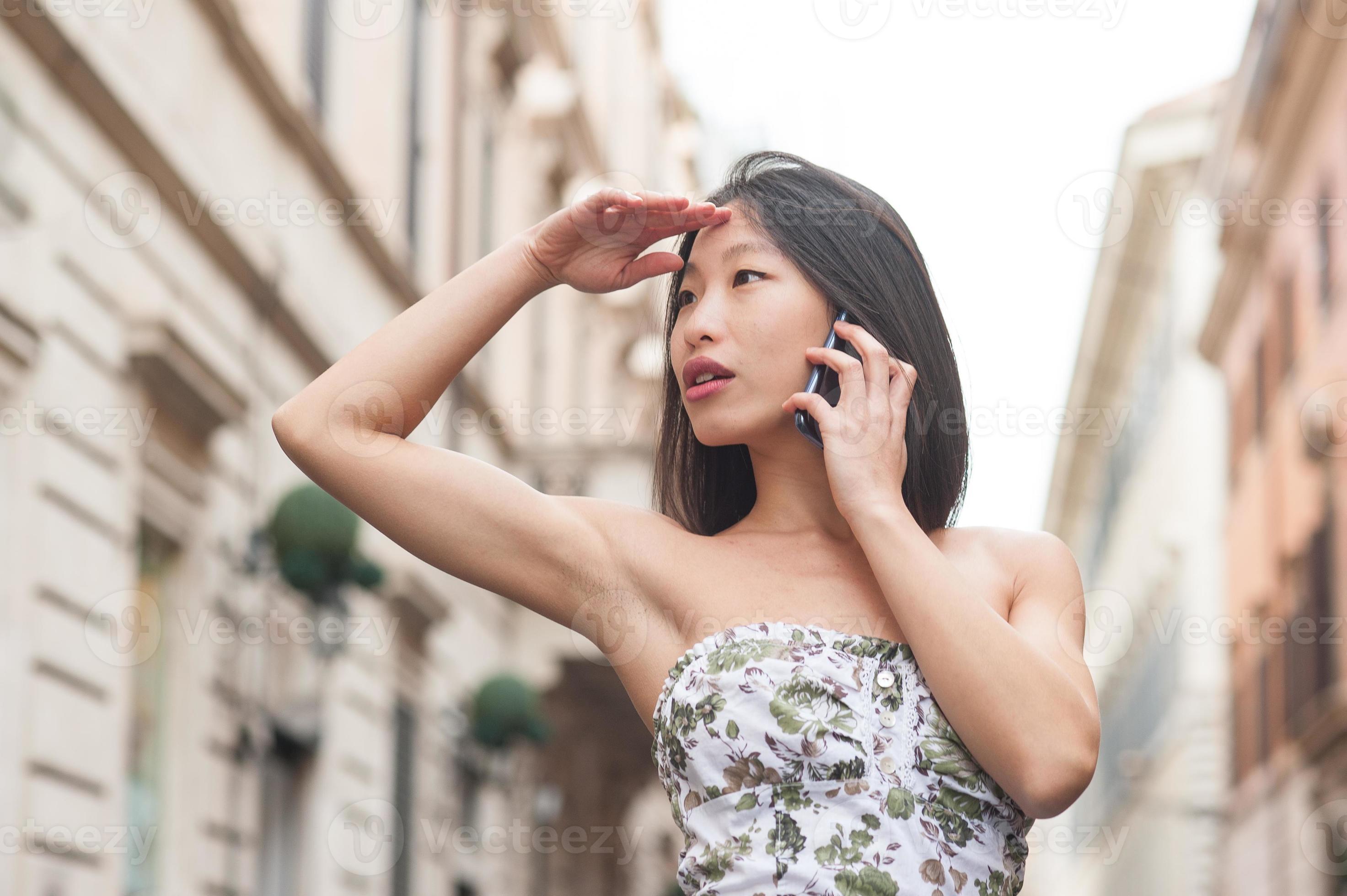 hermosa mujer asiática hablando usando teléfono móvil primavera urbana al aire libre foto