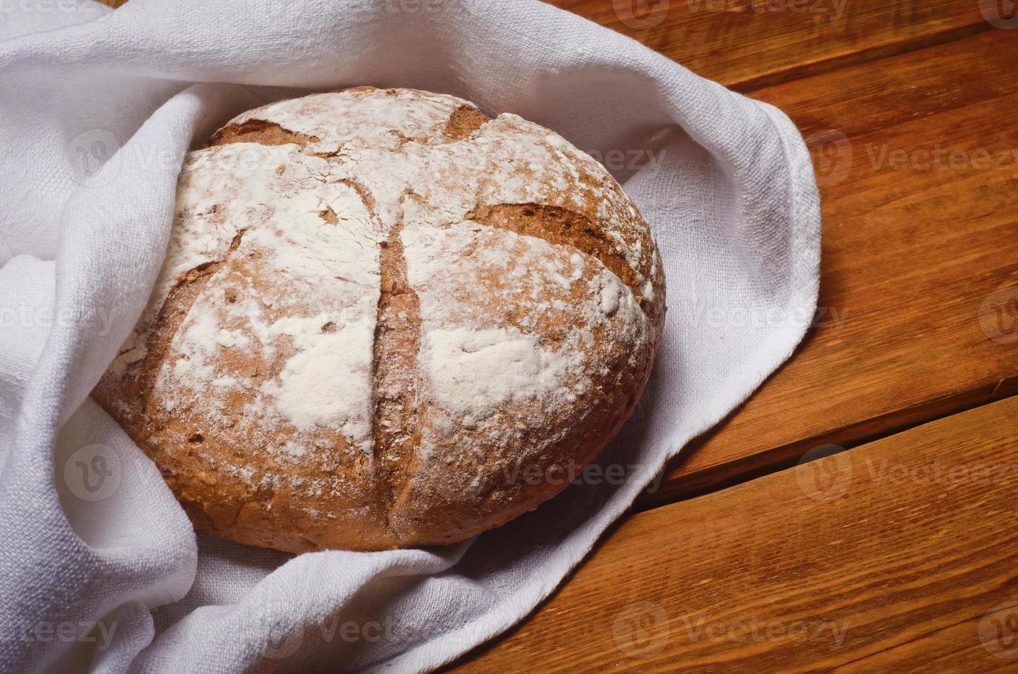 Rosy loaf of bread wrapped in white linen towel photo