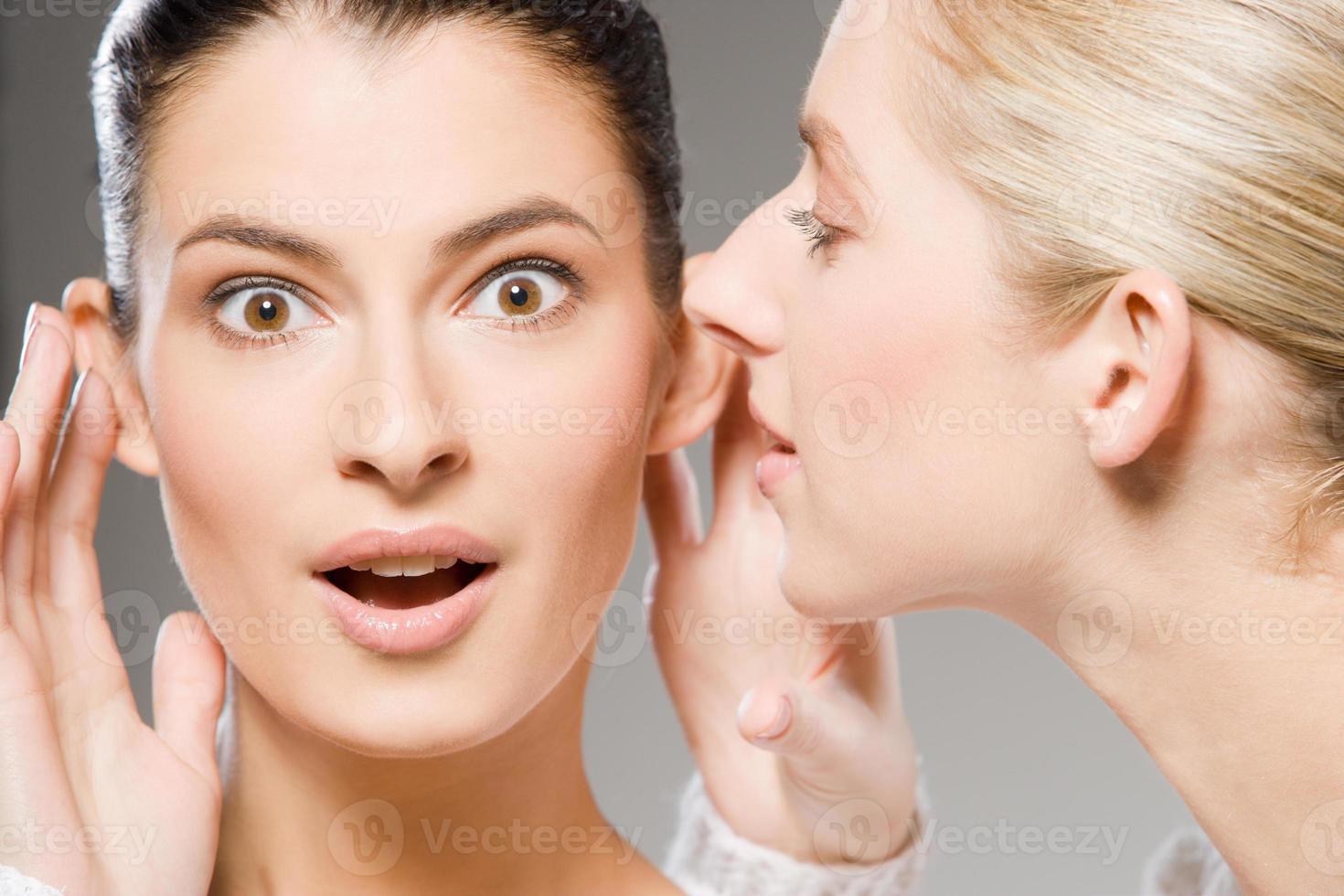 Woman Whispers A Secret To Another Woman Who Looks Shocked 1215542