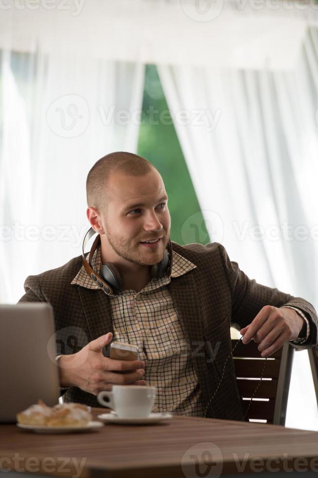 Hombre de negocios descansando en el café y escuchando música con auriculares foto