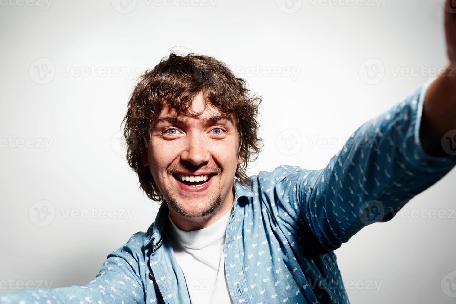 Close up portrait of a young joyful man holding smartphone photo
