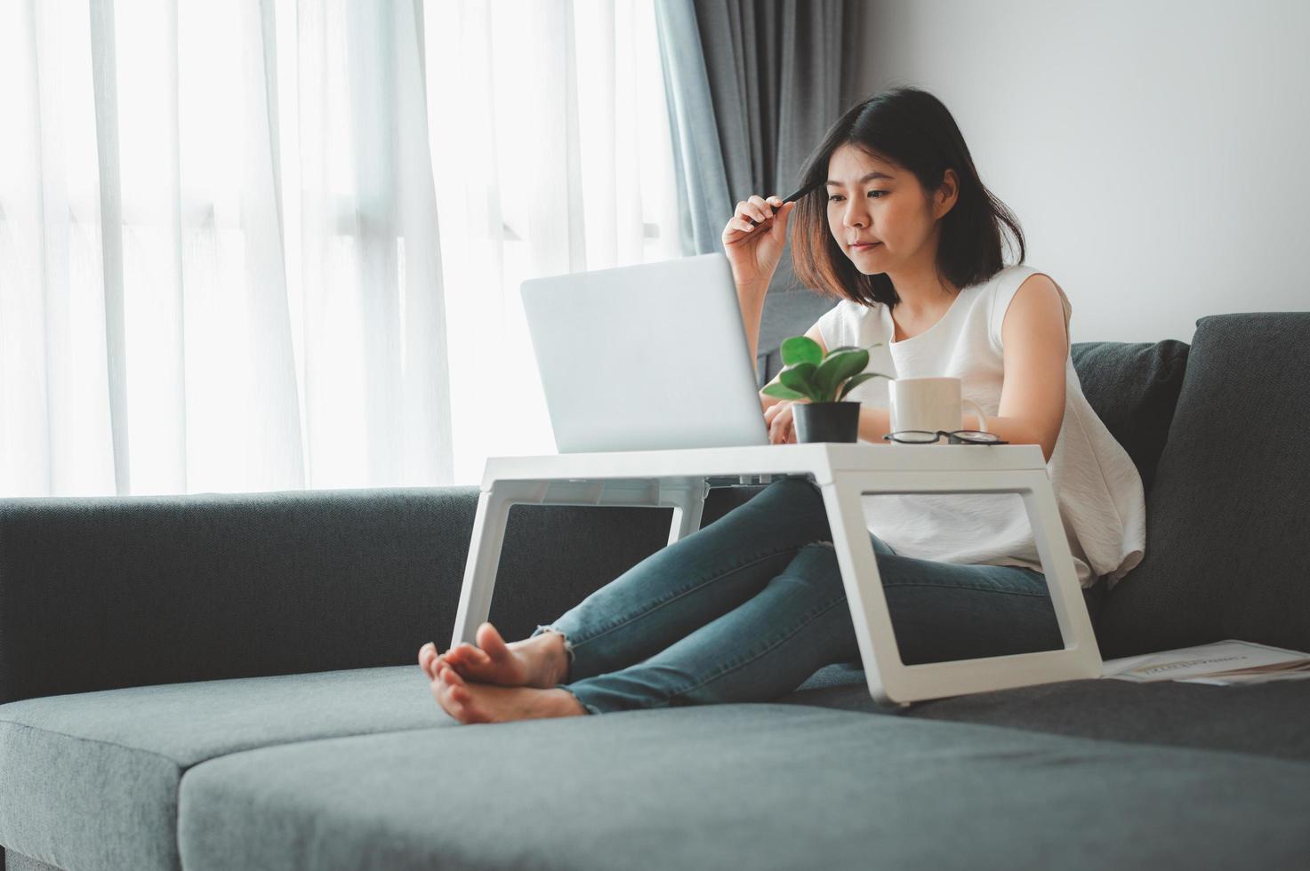 Woman thinking while working at home on sofa photo