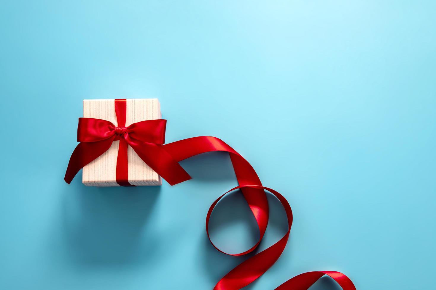 Gift box with red ribbon on blue background  photo