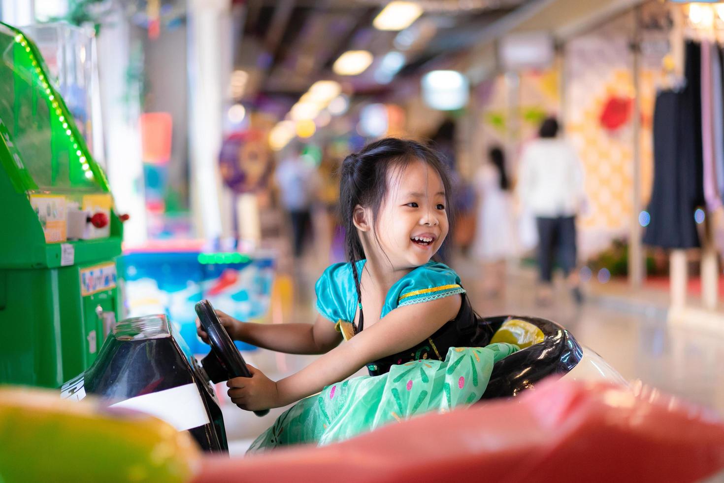 Niña asiática monta en coche de juguete en el centro comercial foto