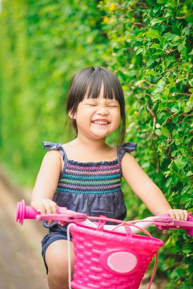 niña feliz monta una bicicleta en el parque foto