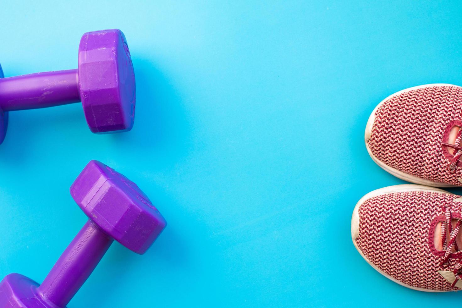 Dumbbells and running shoes on blue background photo