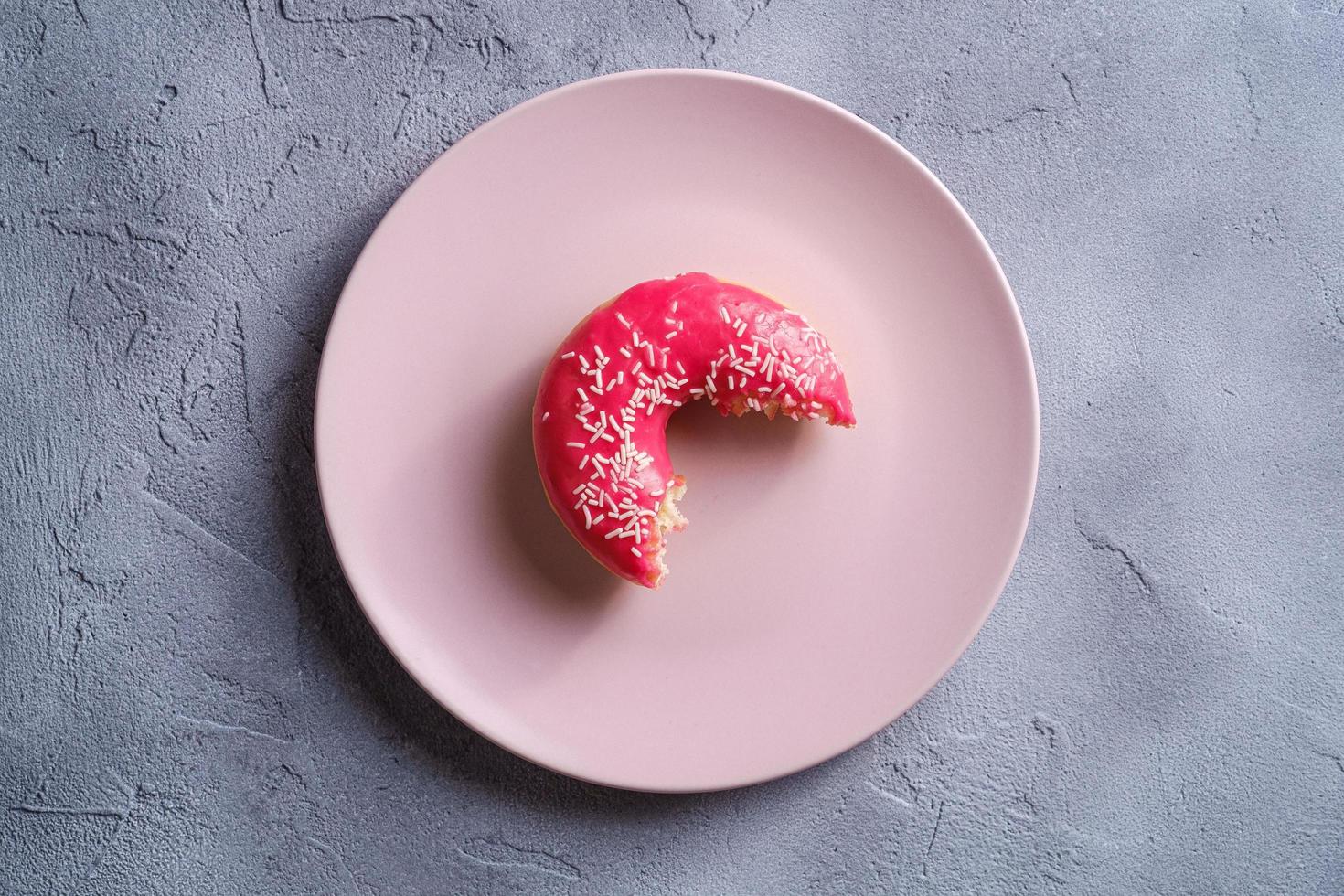 Bitten pink donut with sprinkles  photo