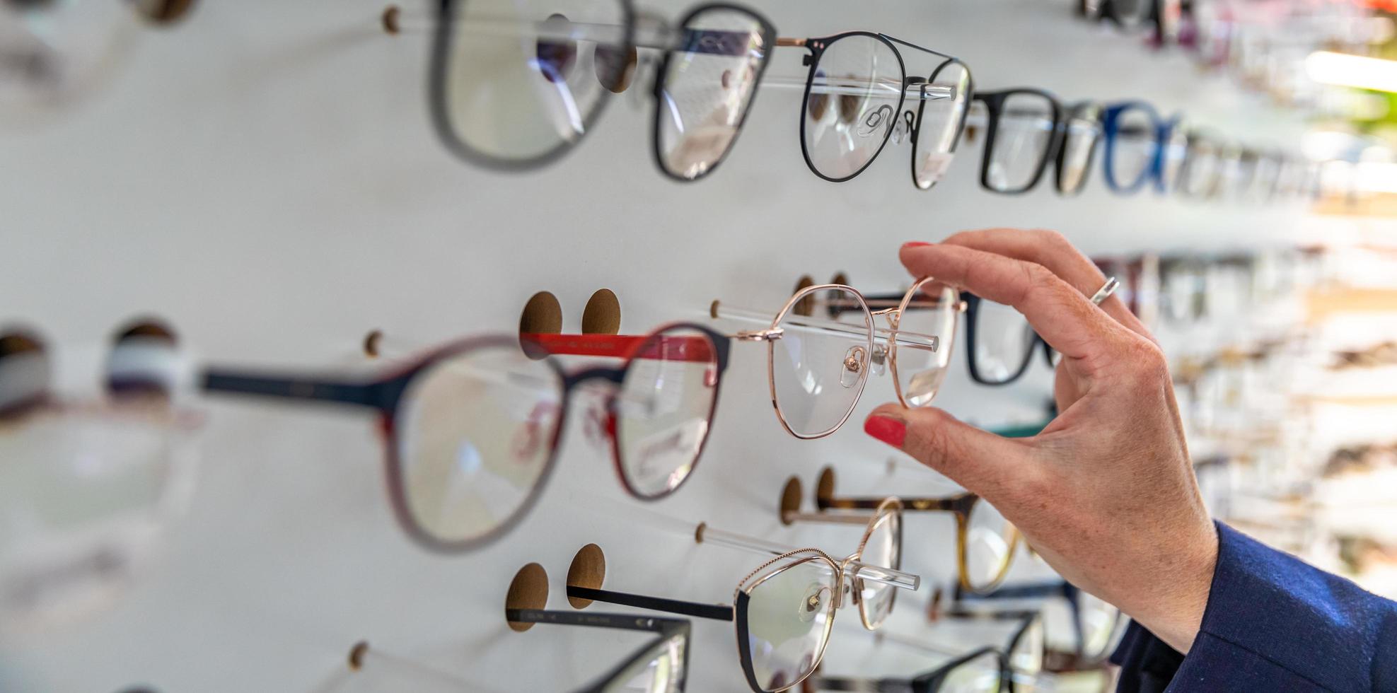 mujer elige gafas en una tienda minorista foto