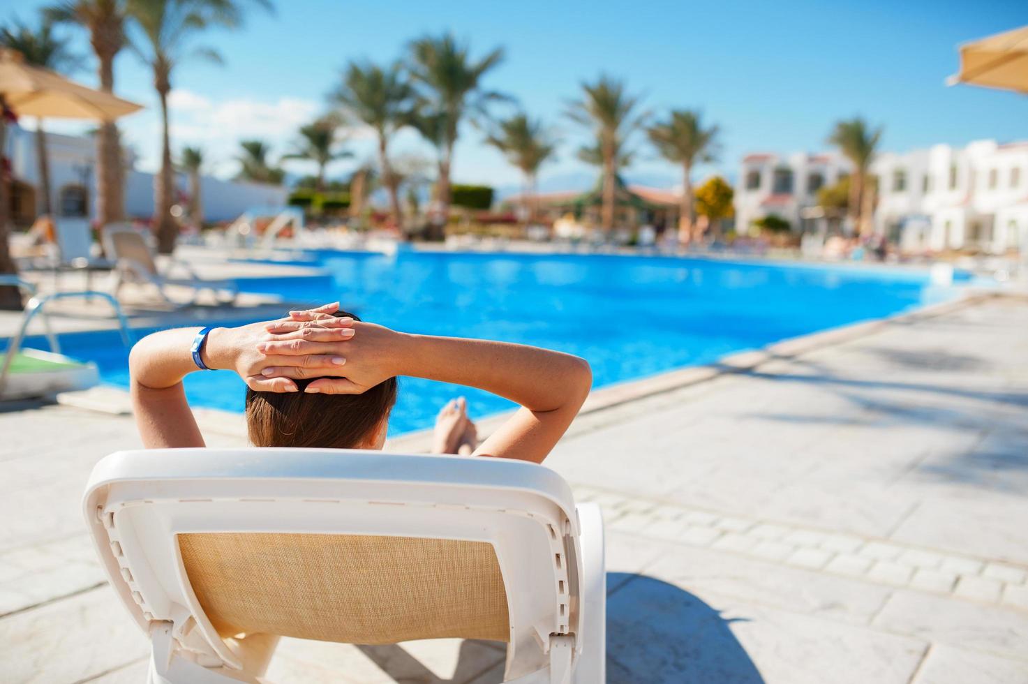 mujer recostada en una tumbona junto a la piscina foto