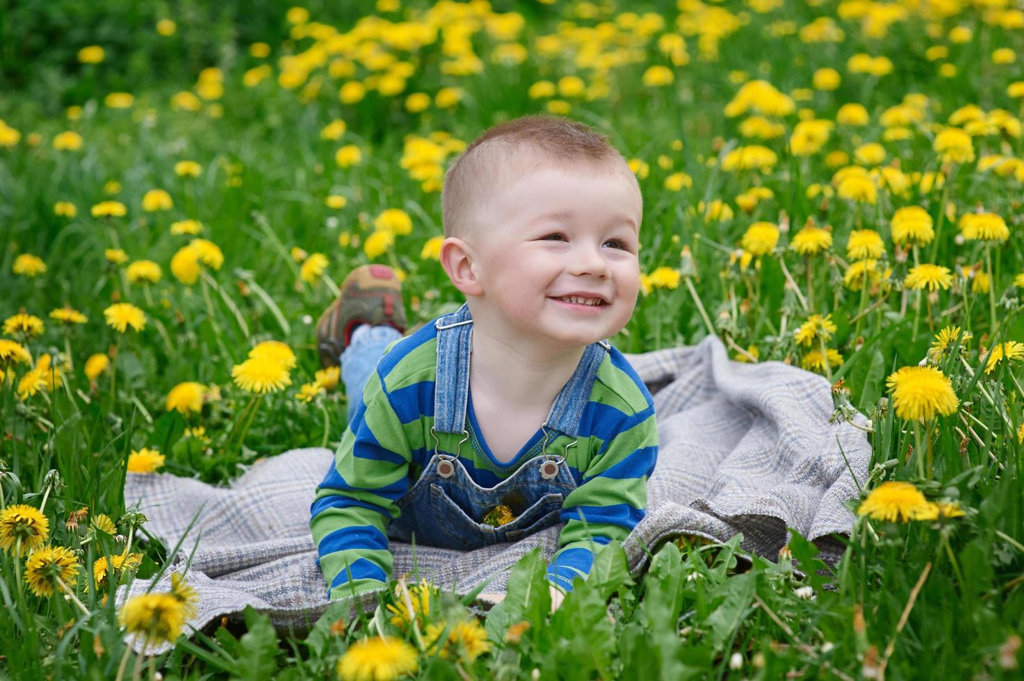 Happy little boy lying on a blanket outdoors photo