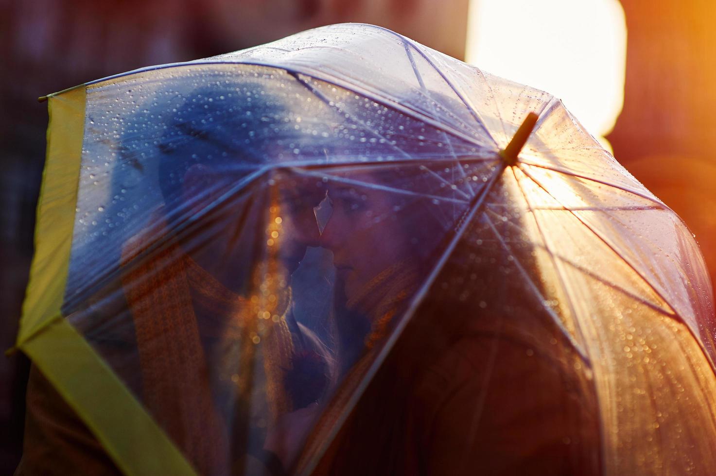 Closeup of young beautiful couple kissing under umbrella photo