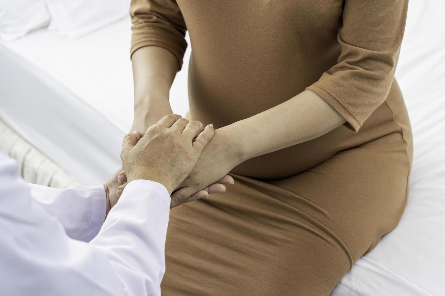 Obstetrician holds hands of pregnant patient photo