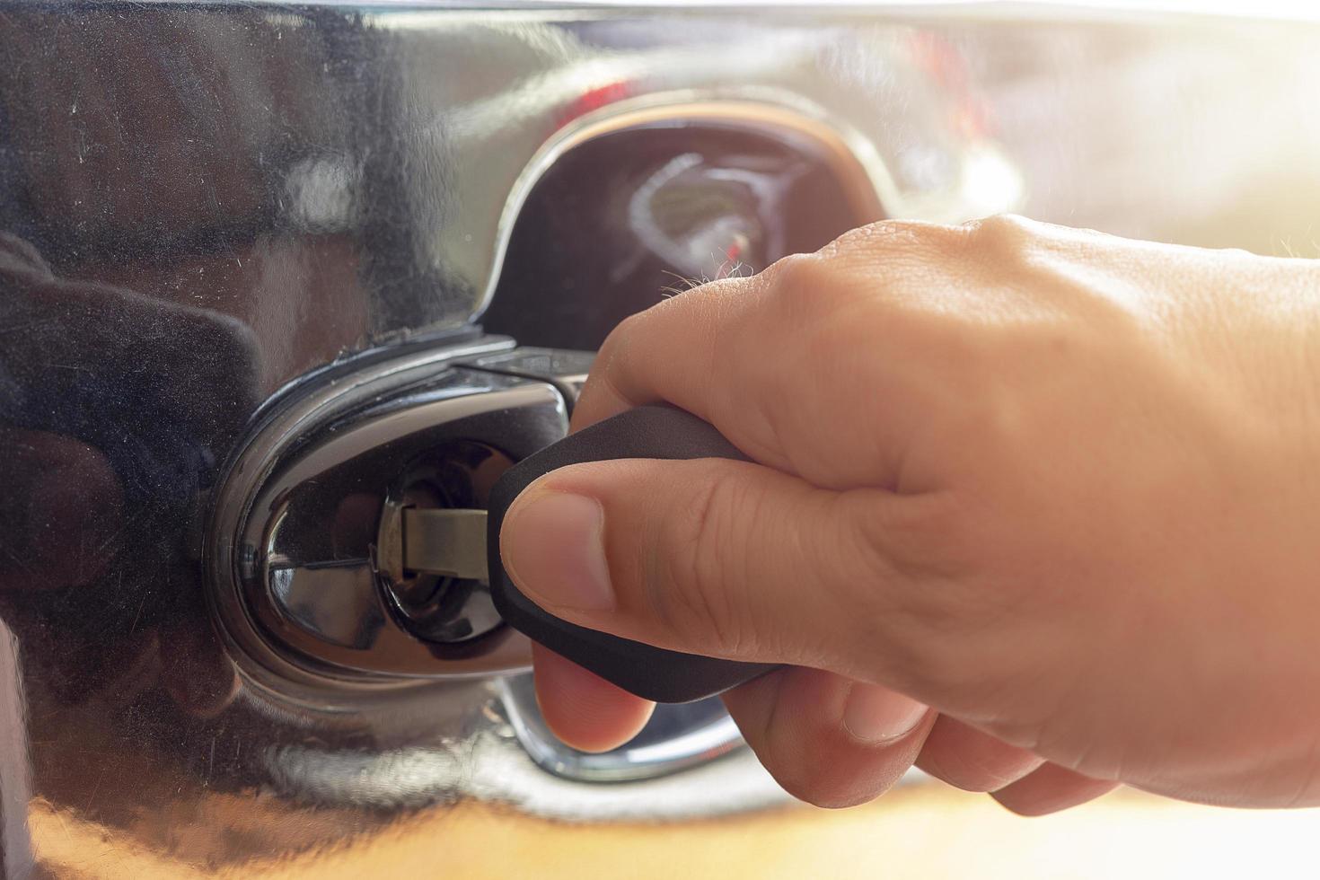 Cerca de la mano insertando una llave en la puerta del coche foto