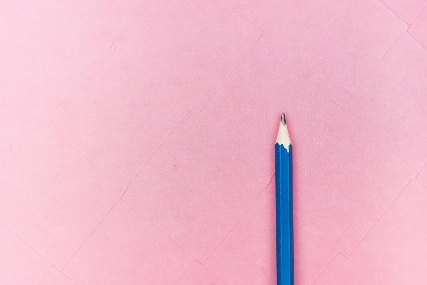 Blue pencil on pink background photo