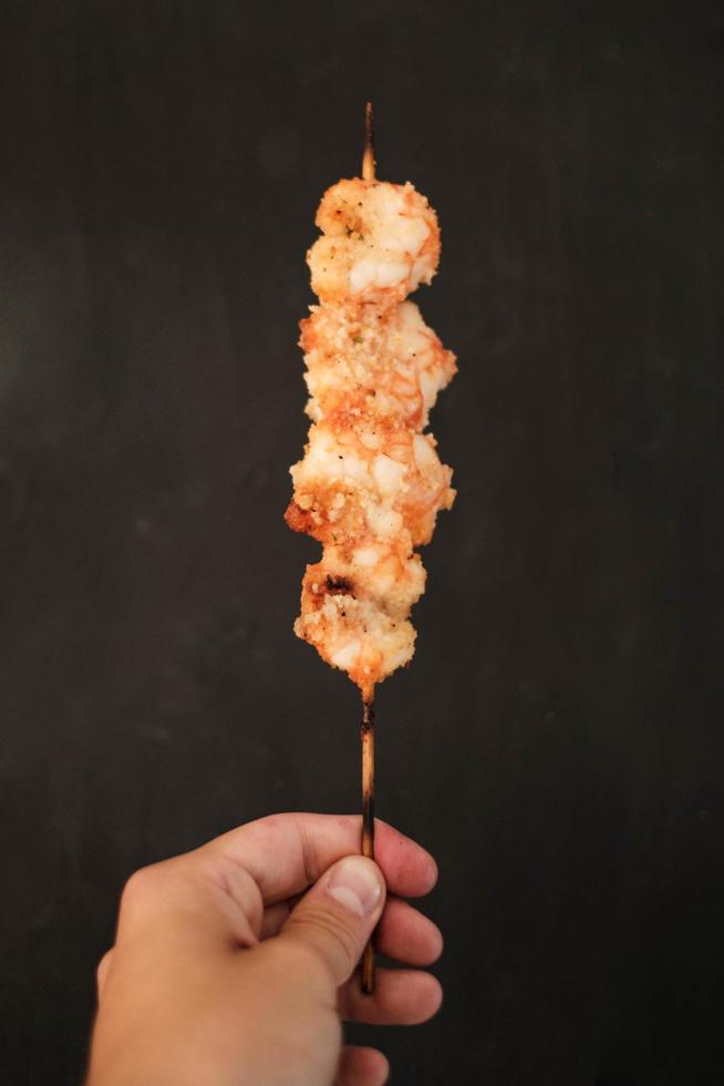 Person holding shrimp skewer photo