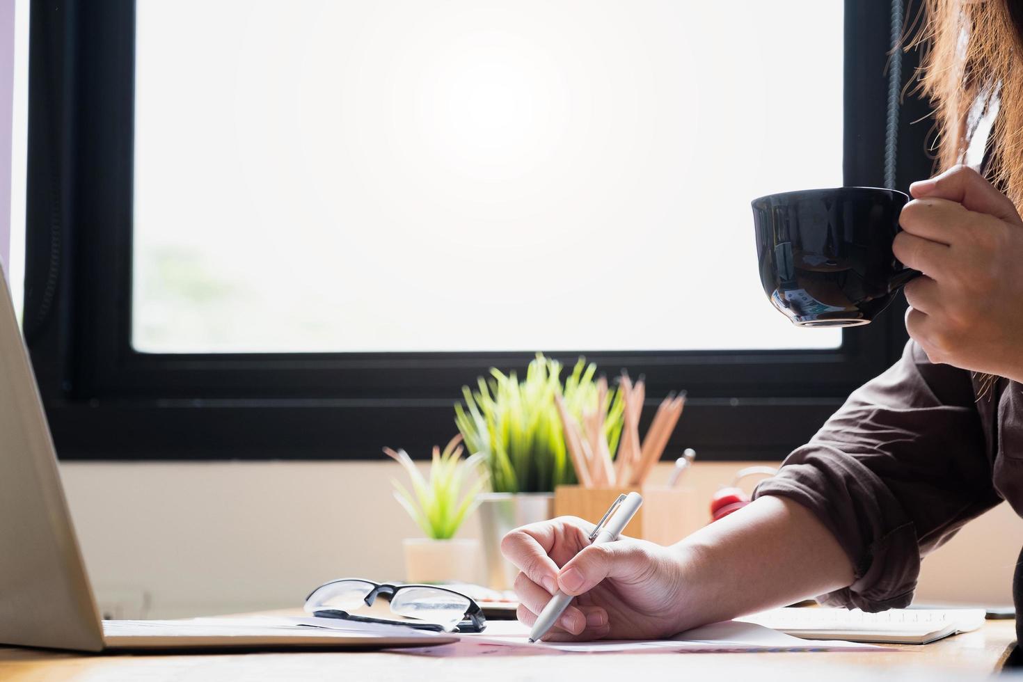 Businesswoman working while holding cup of coffee photo