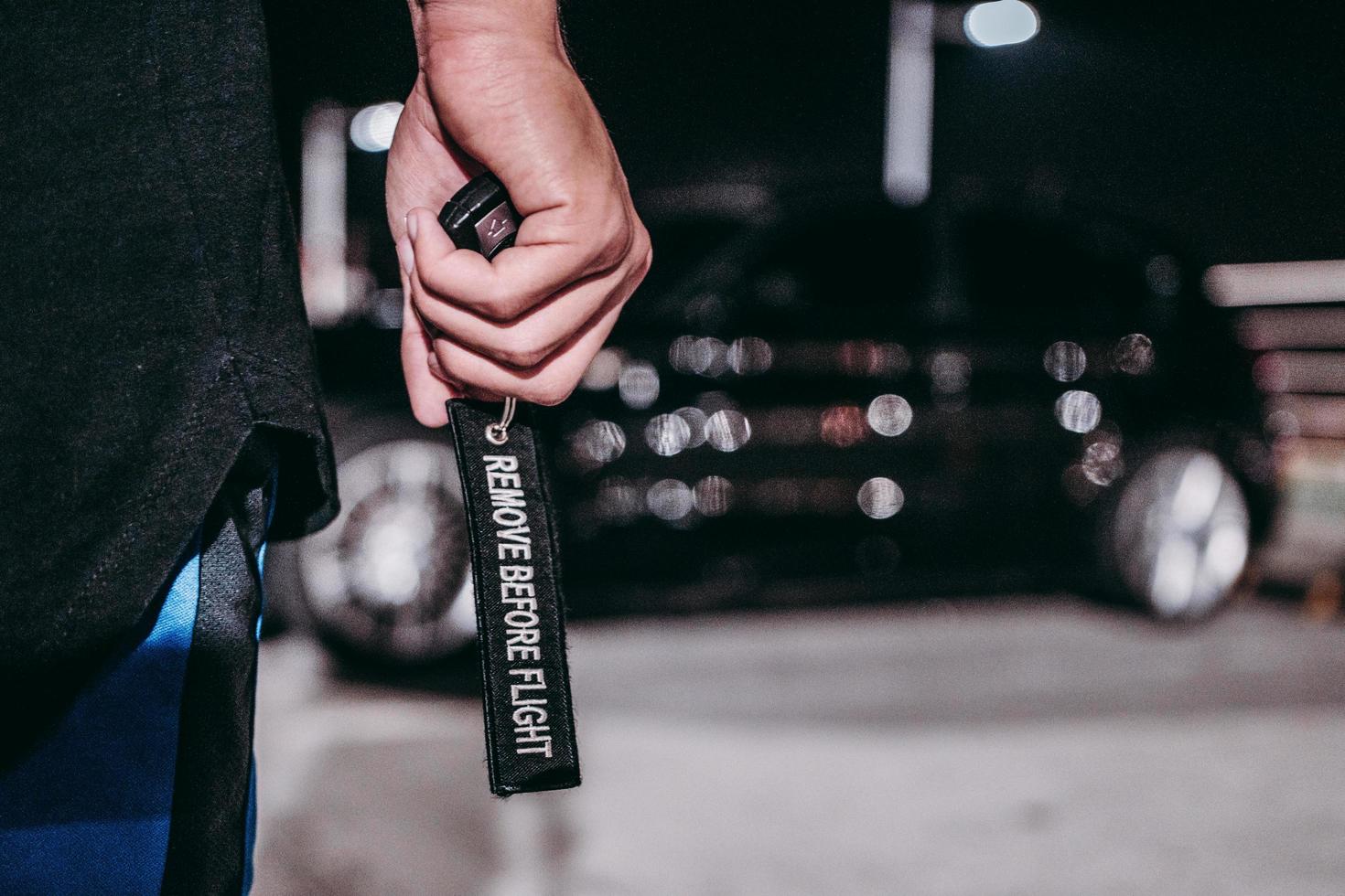 Person holding black key chain with text photo