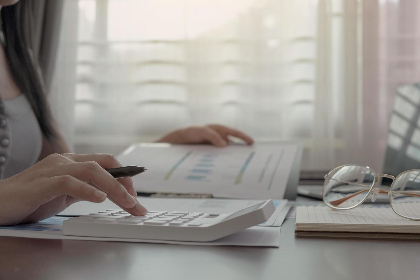 Close-up of woman working on calculator in home office photo