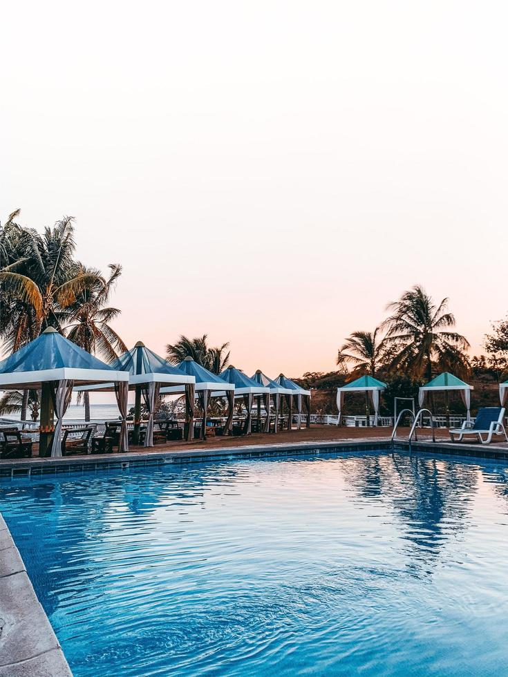 Cabanas by a pool and beach photo