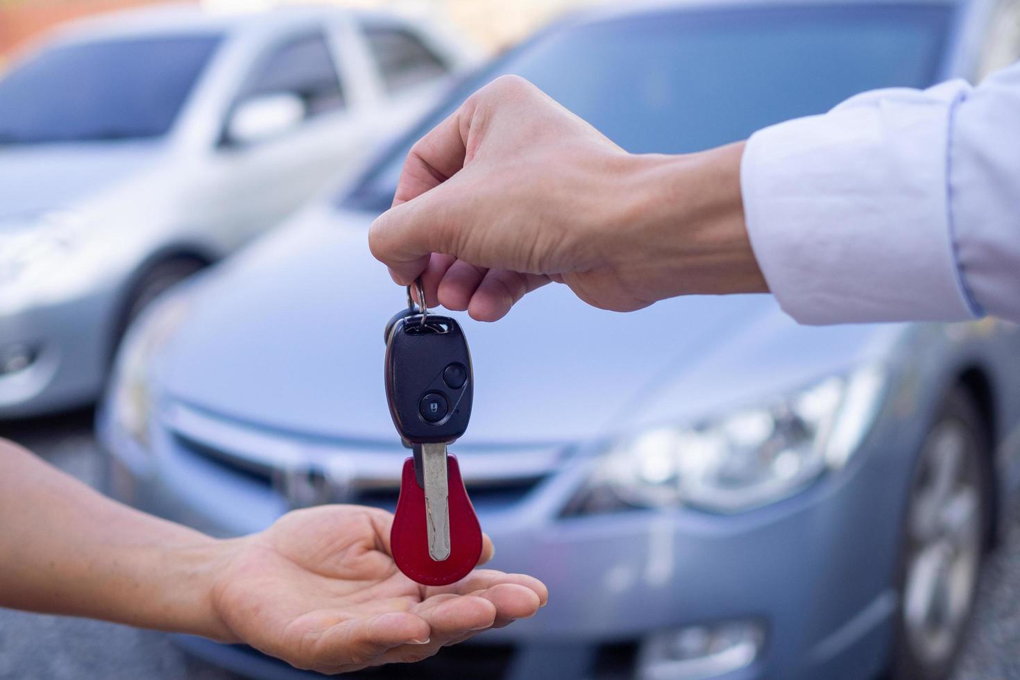 un vendedor de autos entregando una llave al nuevo propietario del vehículo foto