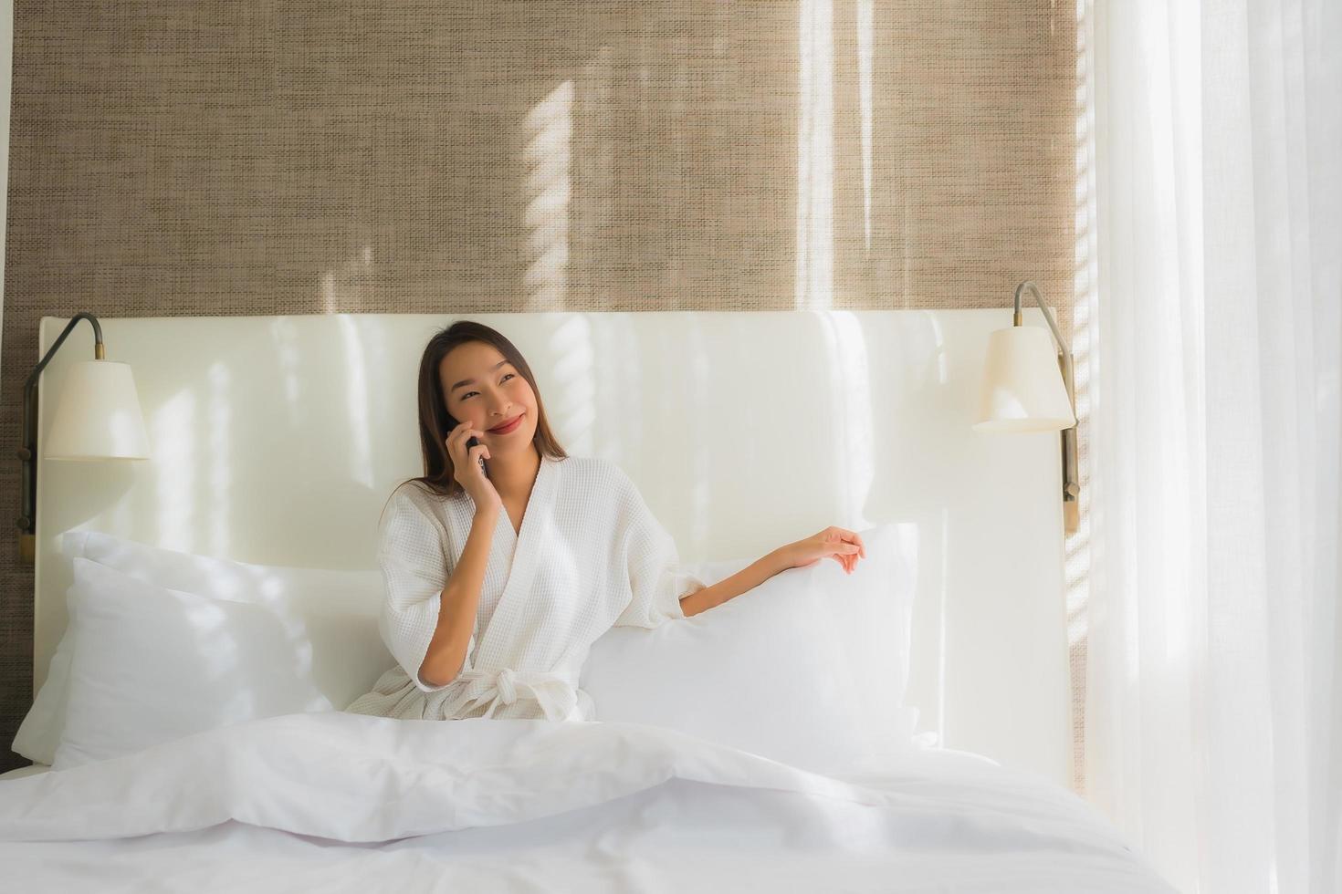 mujer asiática con teléfono inteligente en la cama foto