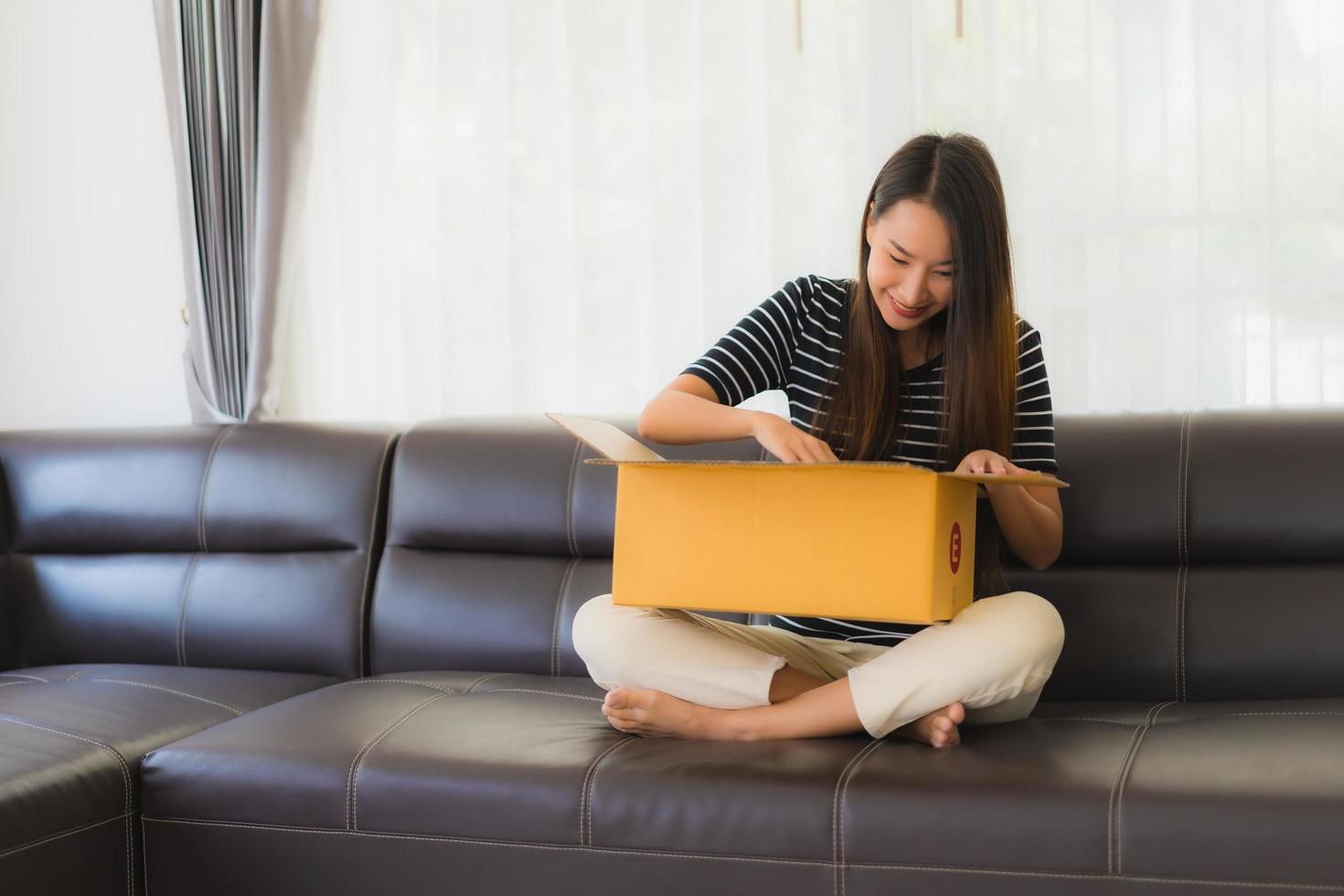 mujer abriendo la caja de cartón en el sofá foto