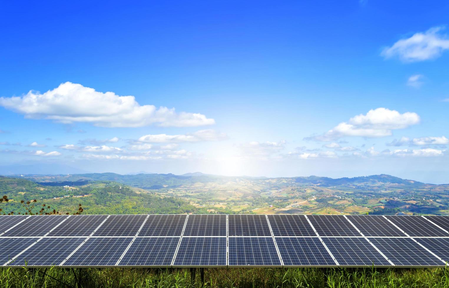 un campo de paneles solares de energía se asienta sobre una montaña bajo un cielo azul foto