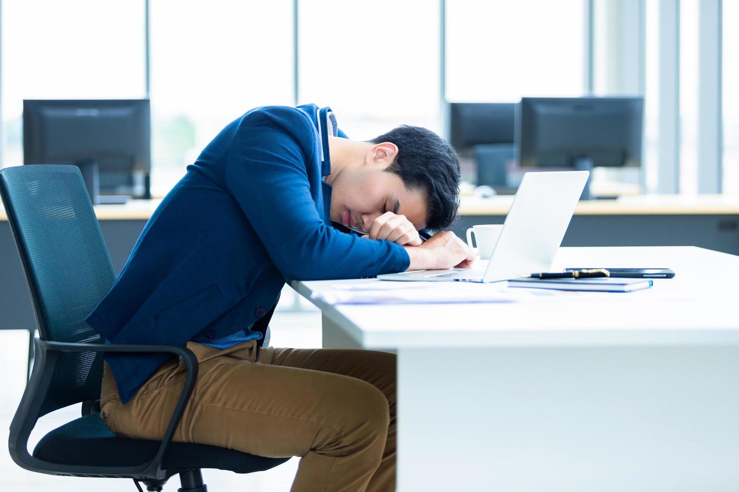 joven empresario asiático tomando una siesta en el trabajo foto
