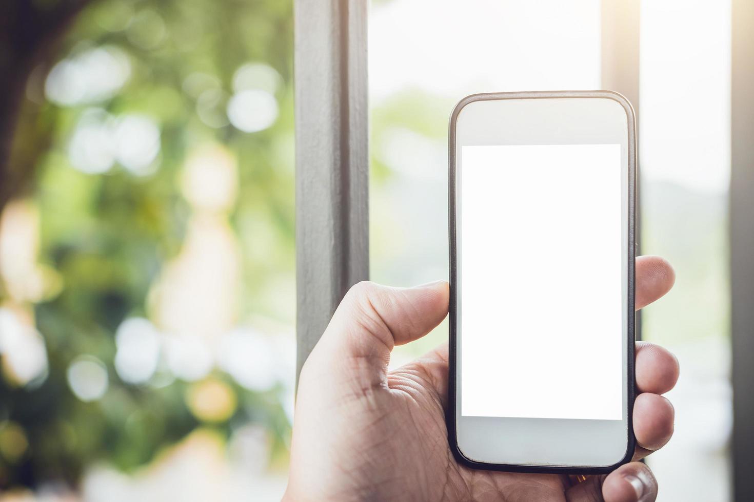 hombre que sostiene el teléfono inteligente con pantalla en blanco foto