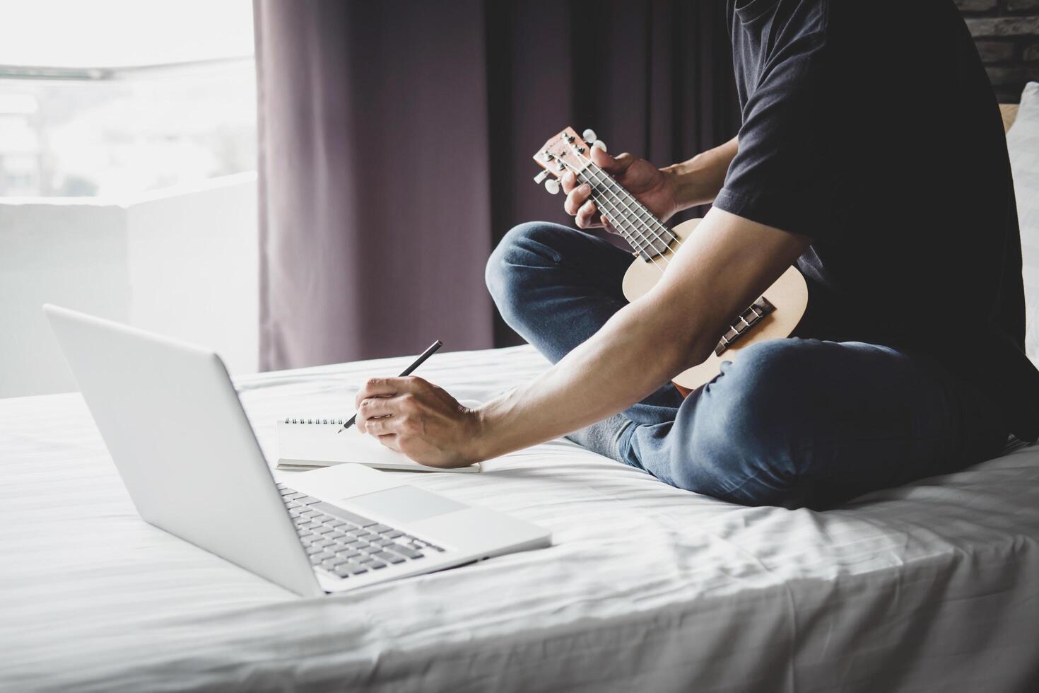 Young man on bed plays music with guitar  photo