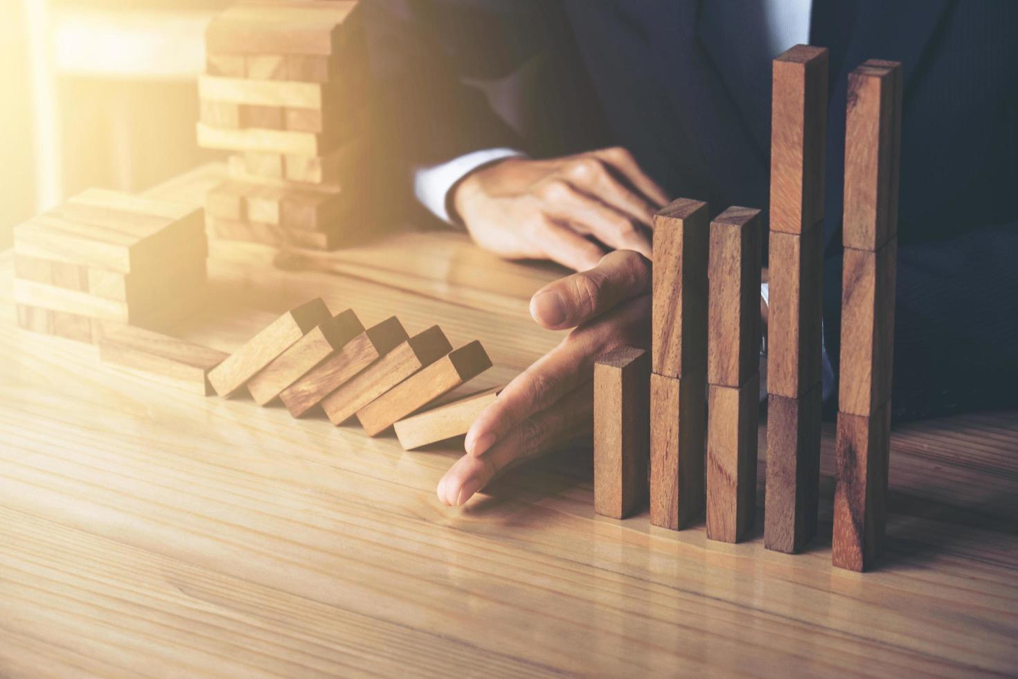 Businessman preventing wood blocks falling photo
