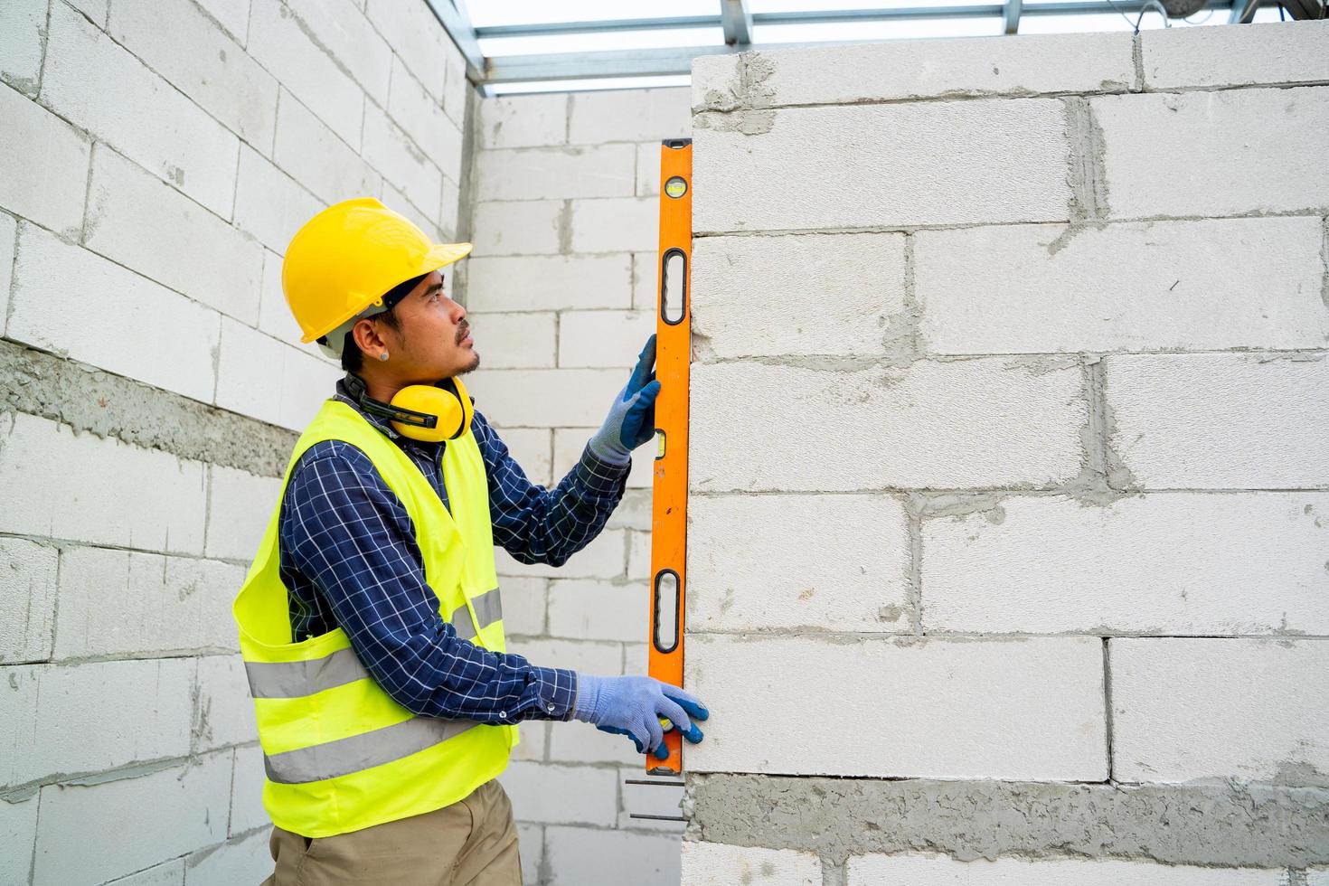 El ingeniero mide el trabajo de la pared de bloques de concreto livianos con un nivel en el sitio de construcción. foto