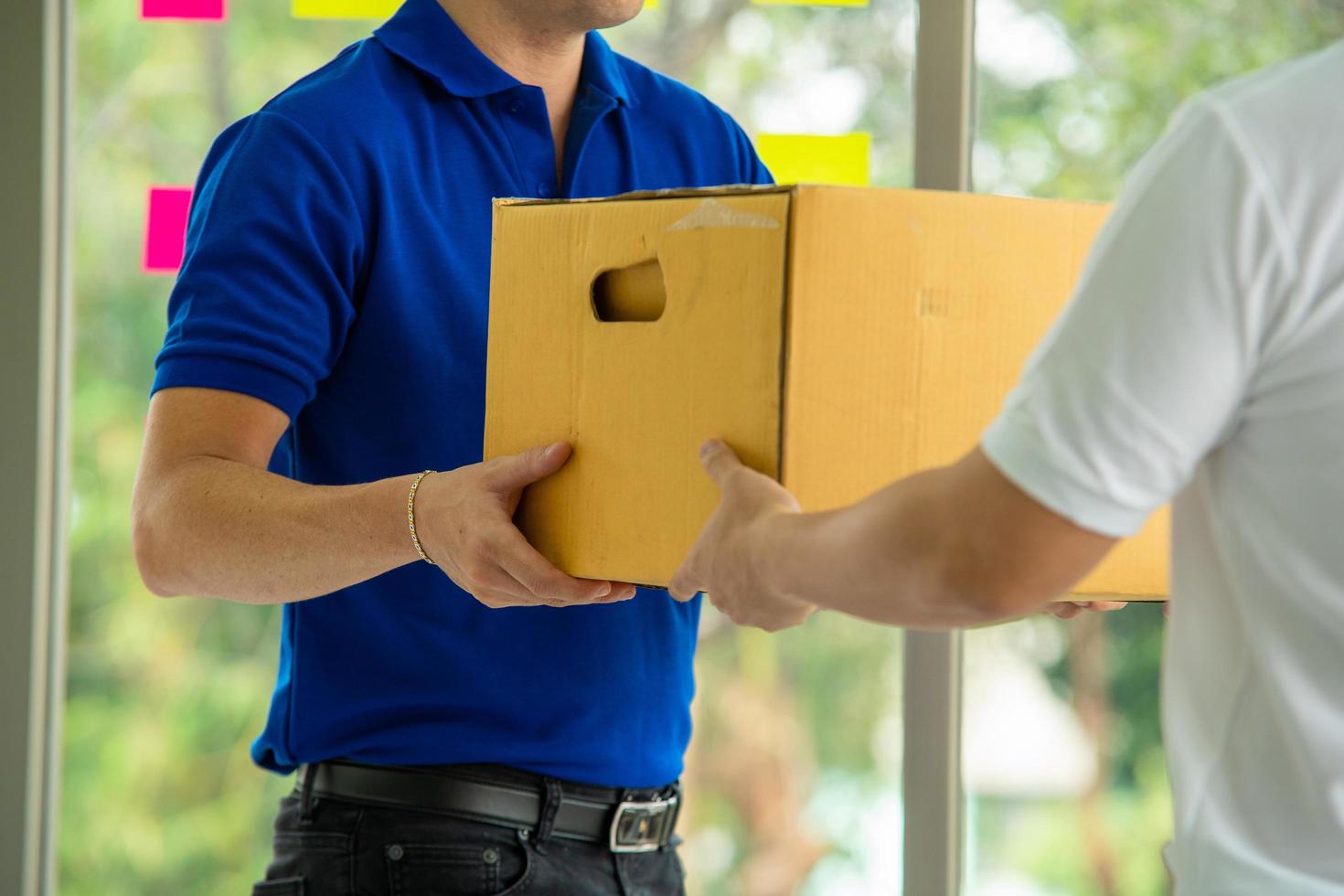 Postal worker hands cardboard box to client photo