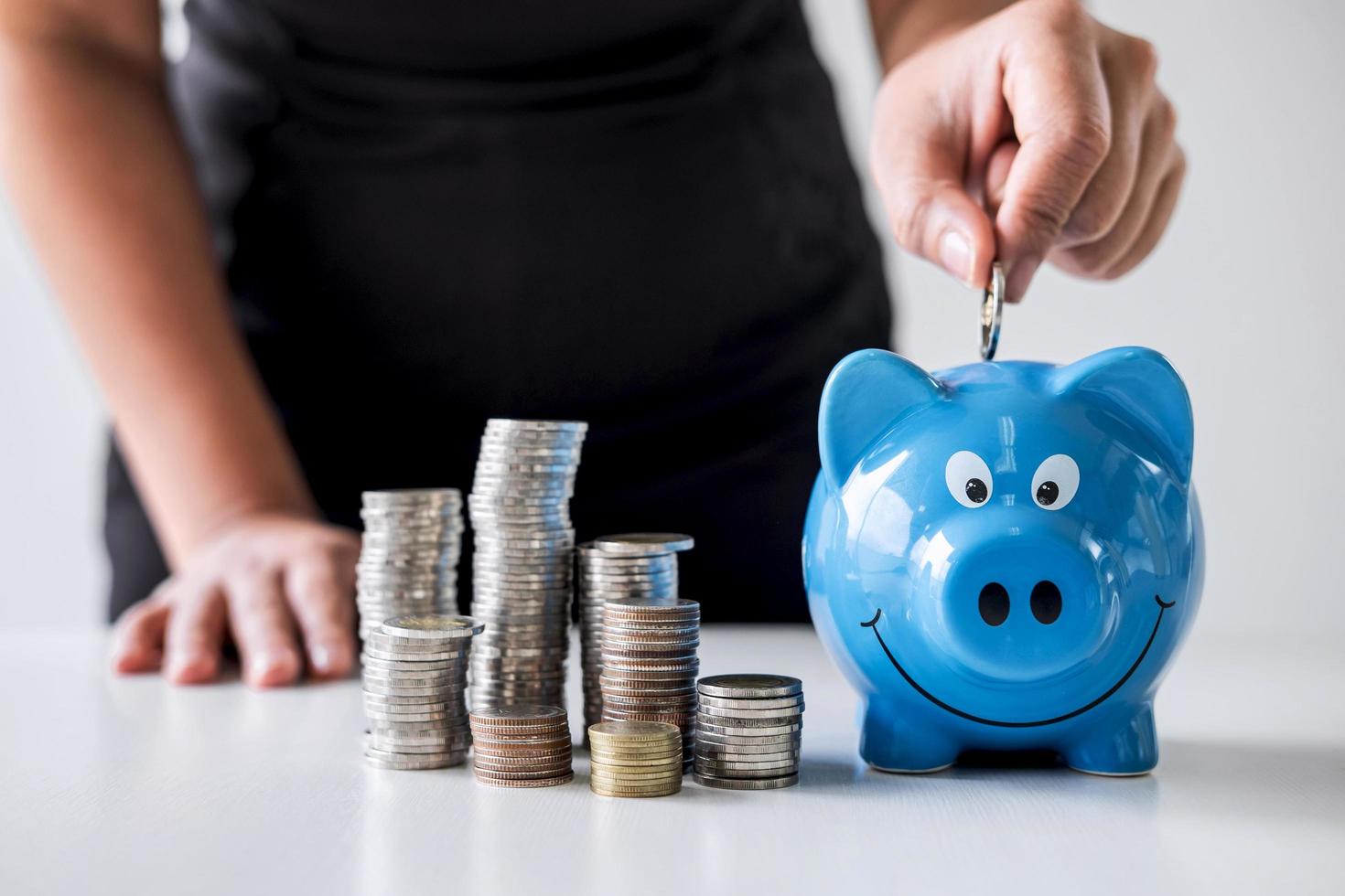 Person putting money into piggy bank photo