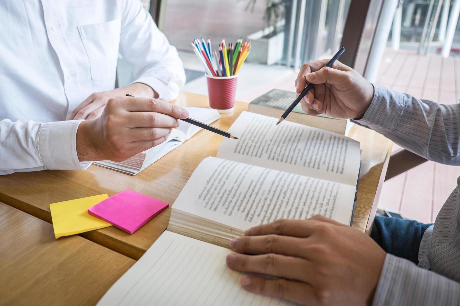 Two people studying and pointing at text on book photo