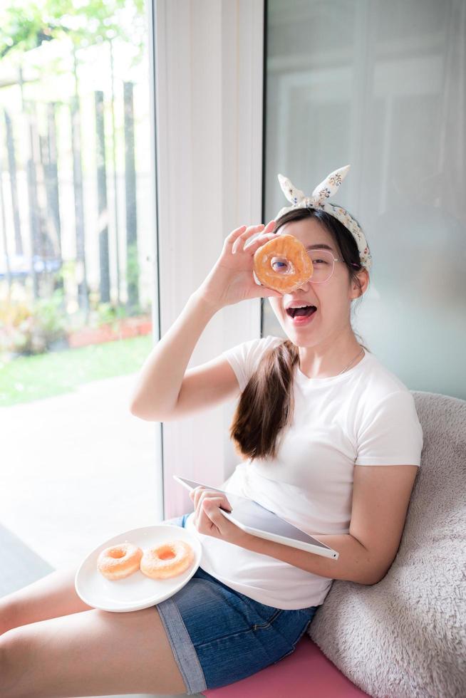 mujer asiática con donut y tableta foto