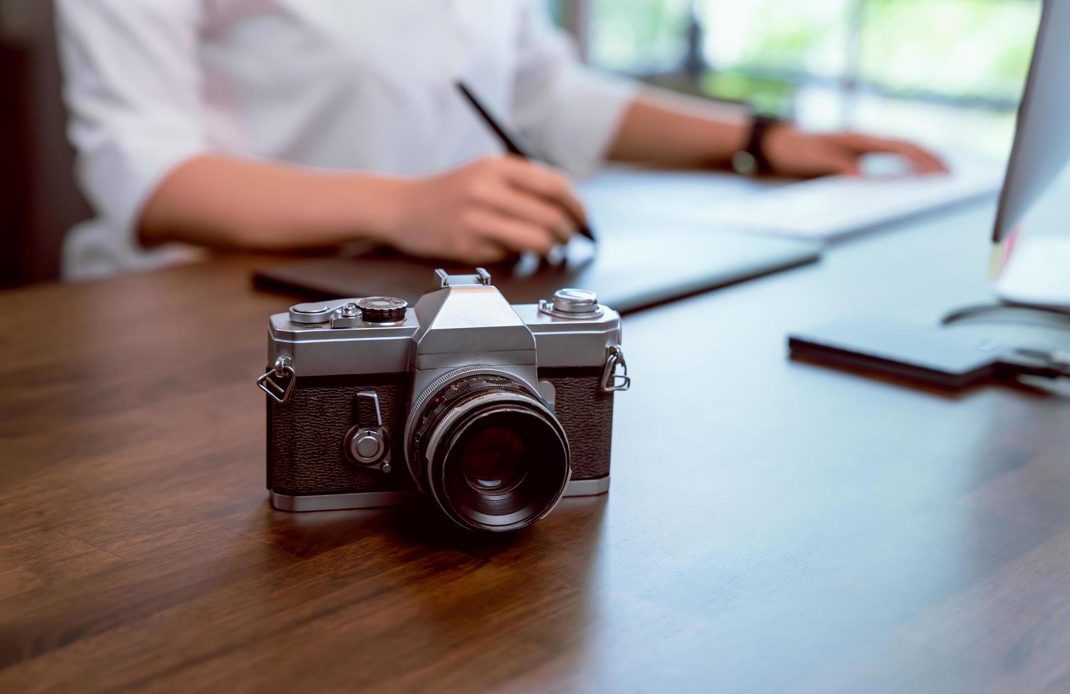 Film camera on desk with woman editing photos 