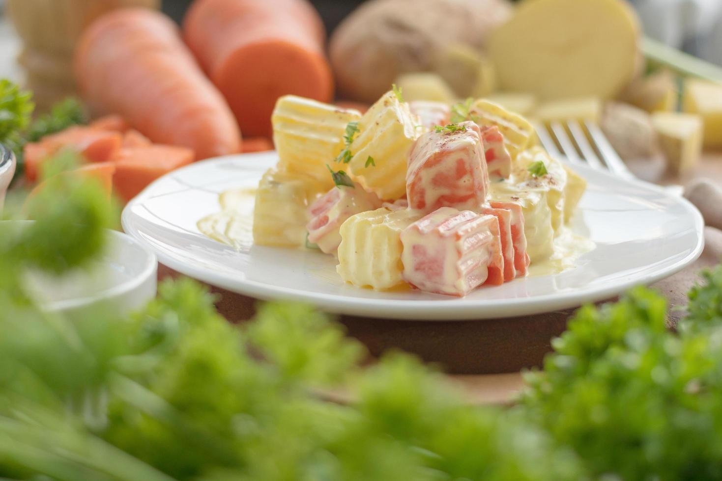 Potato salad on white plate with vegetables photo