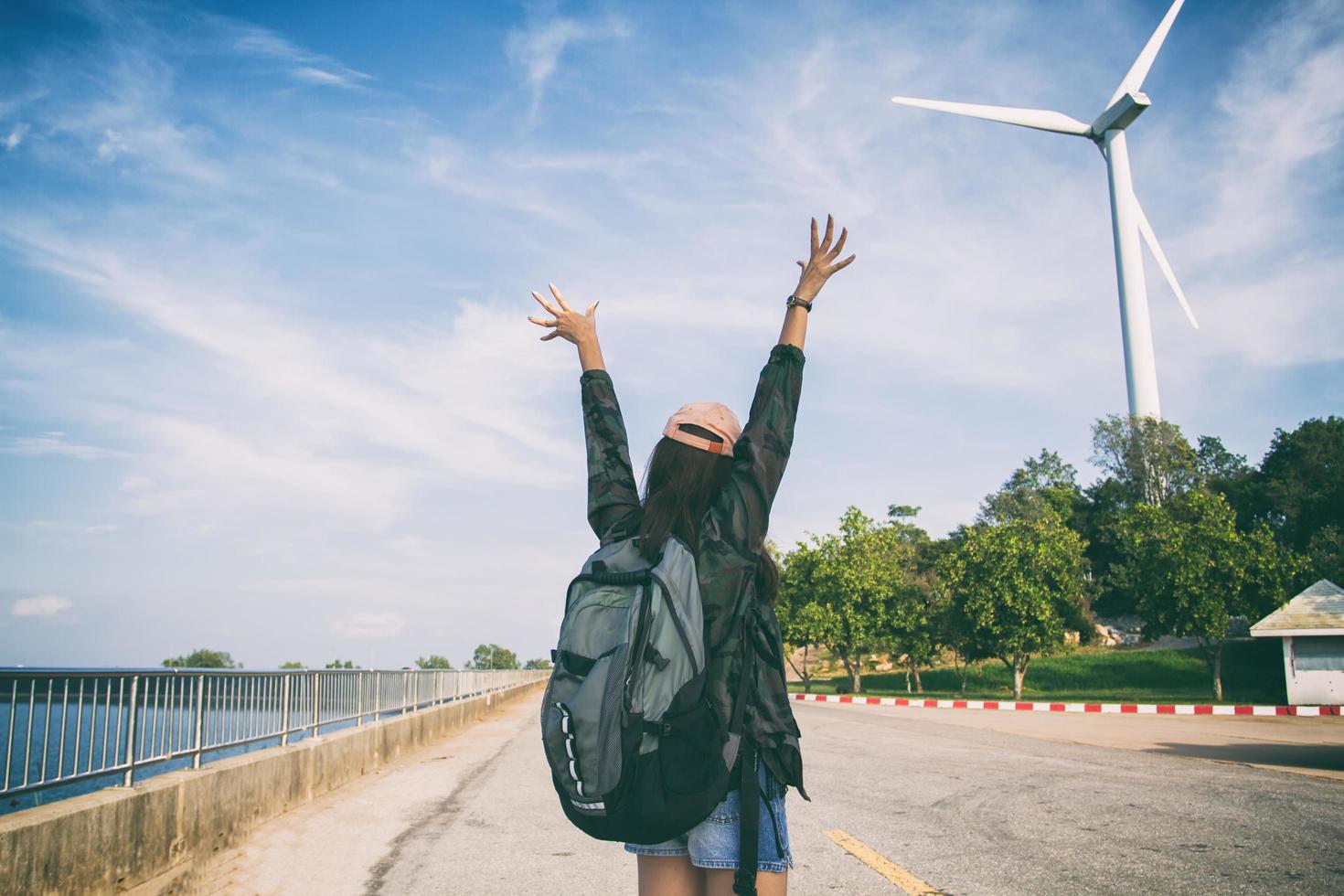 Woman standing with raised arms with backpack on photo