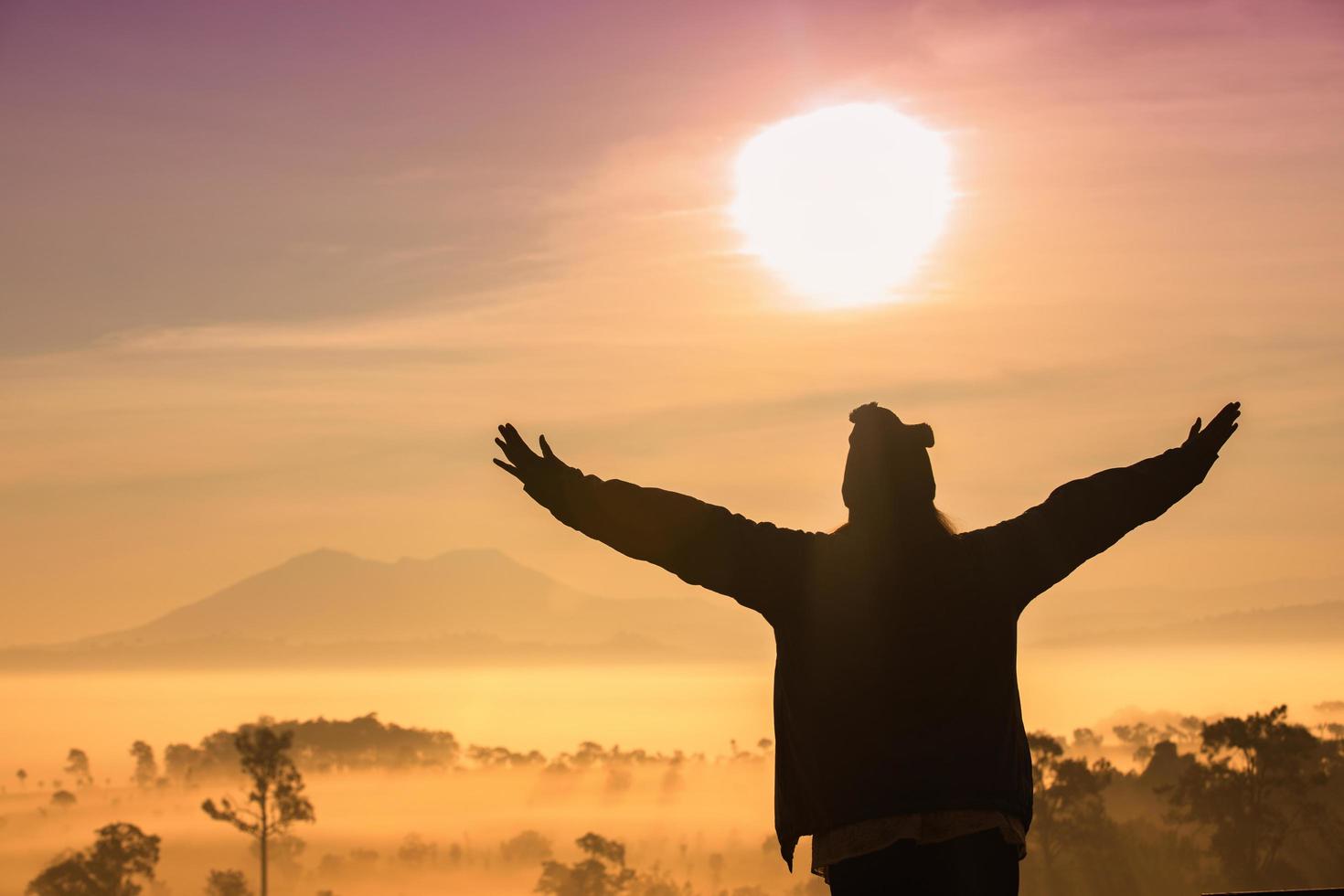 Silhouette of women with raised arms in front of sunset photo