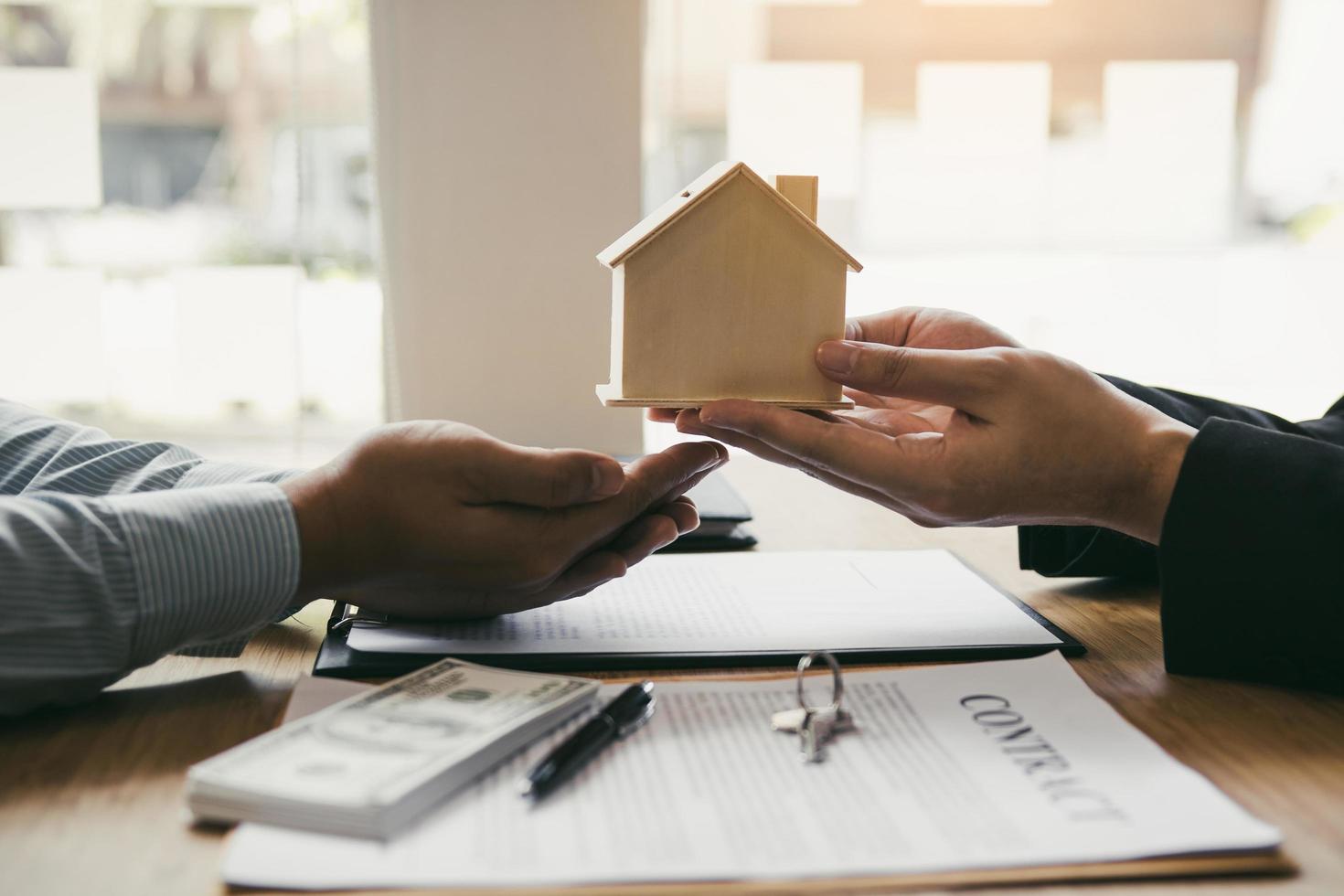 Real estate agent hands wooden house to client photo