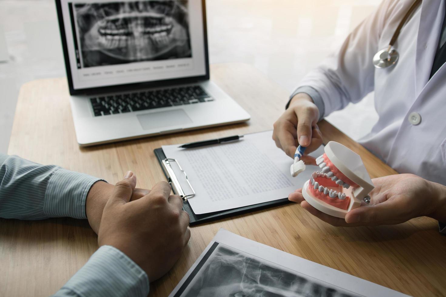 dentista que muestra al cliente cómo limpiar los dientes foto