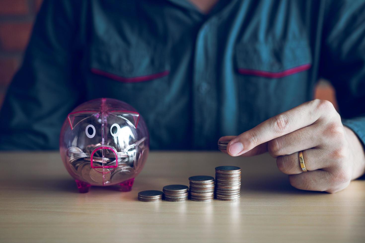 Man stacking coins next to piggy bank photo