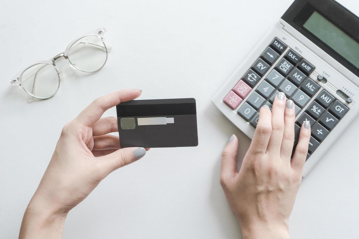 Close-up of woman holding credit card and using calculator photo