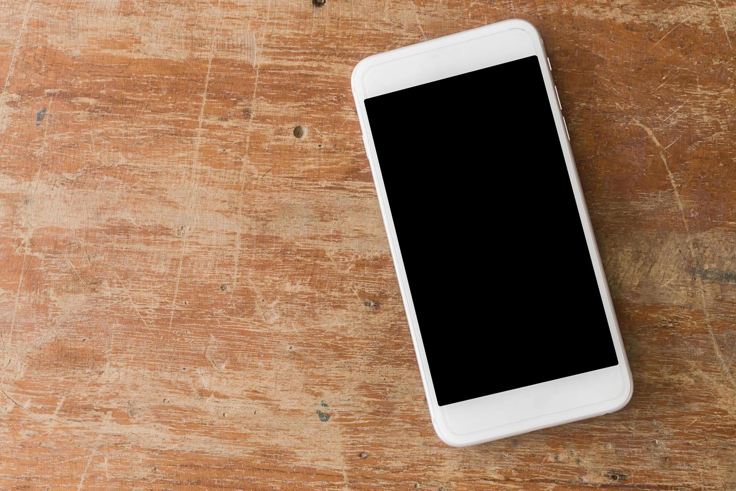 teléfono móvil blanco sobre mesa de madera foto