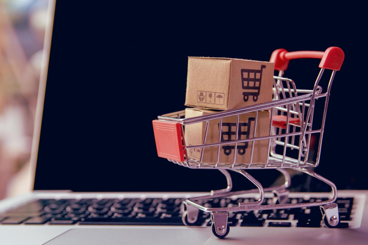 Close-up of miniature shopping cart on laptop photo