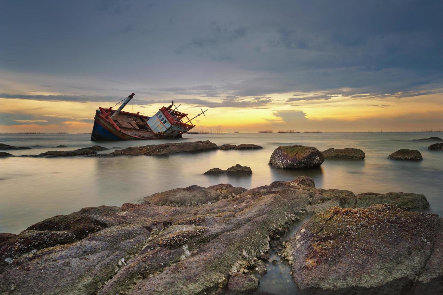 barco naufragado al atardecer foto